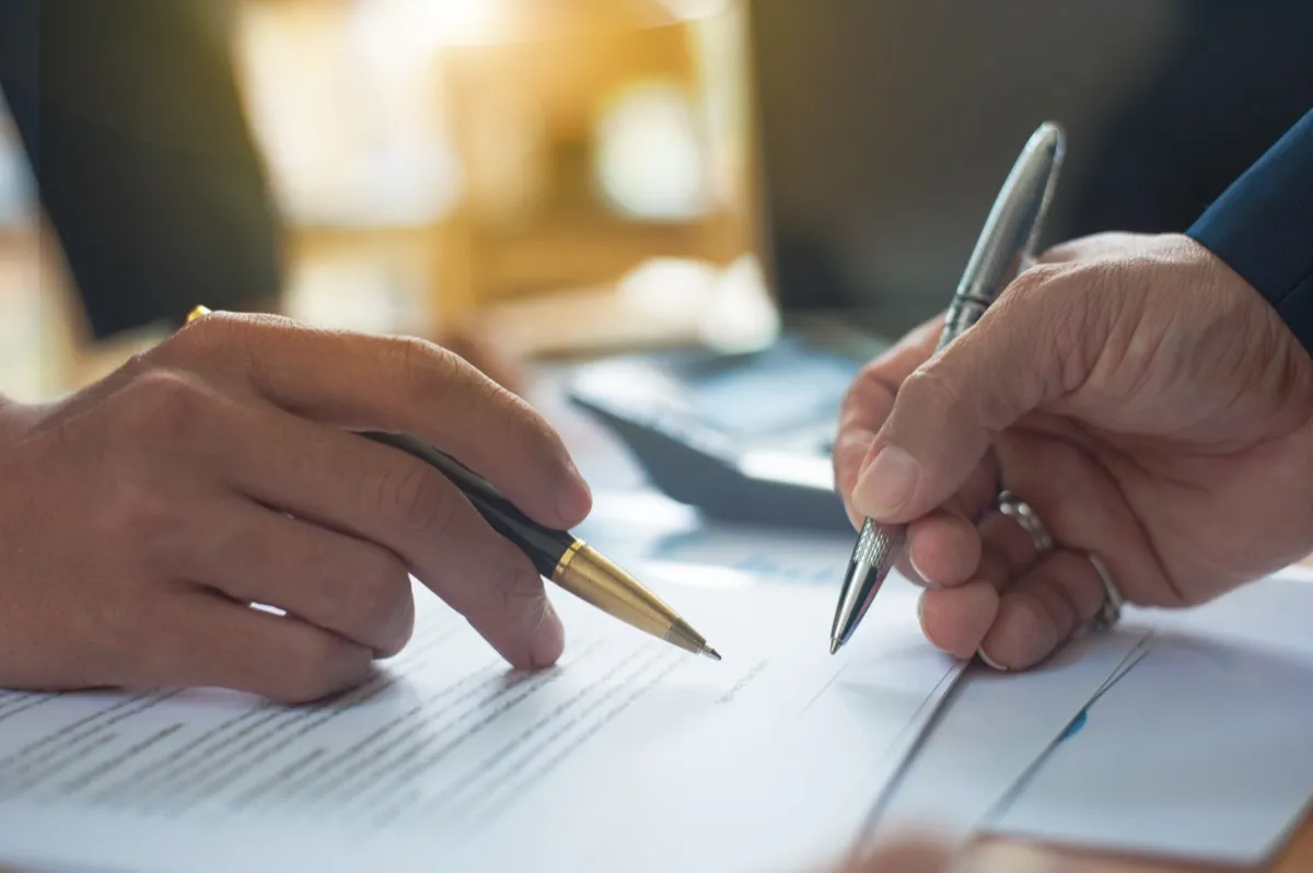 Persona de negocios firmando contrato de arrendamiento sobre mesa de reuniones