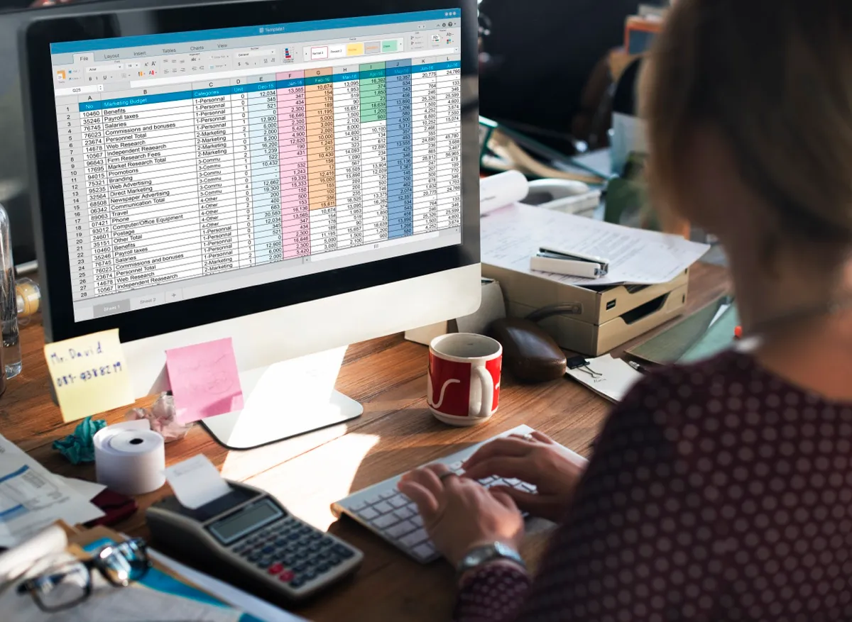 Hoja de cálculo con tablas de datos y control financiero sobre escritorio de trabajo